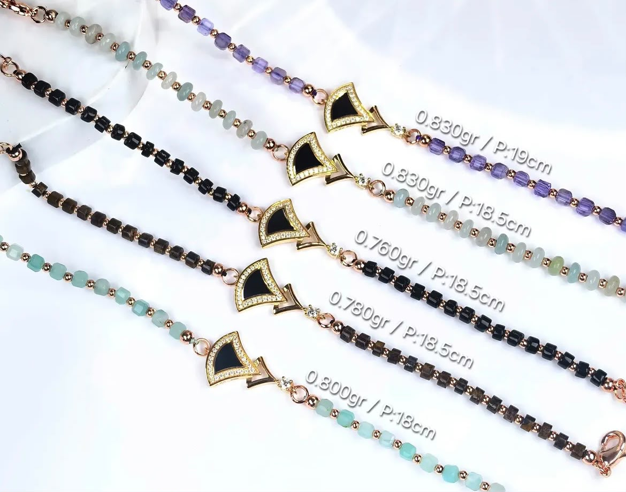Deretan gelang emas manik-manik batu berbagai warna dengan liontin bentuk kipas berkilau.